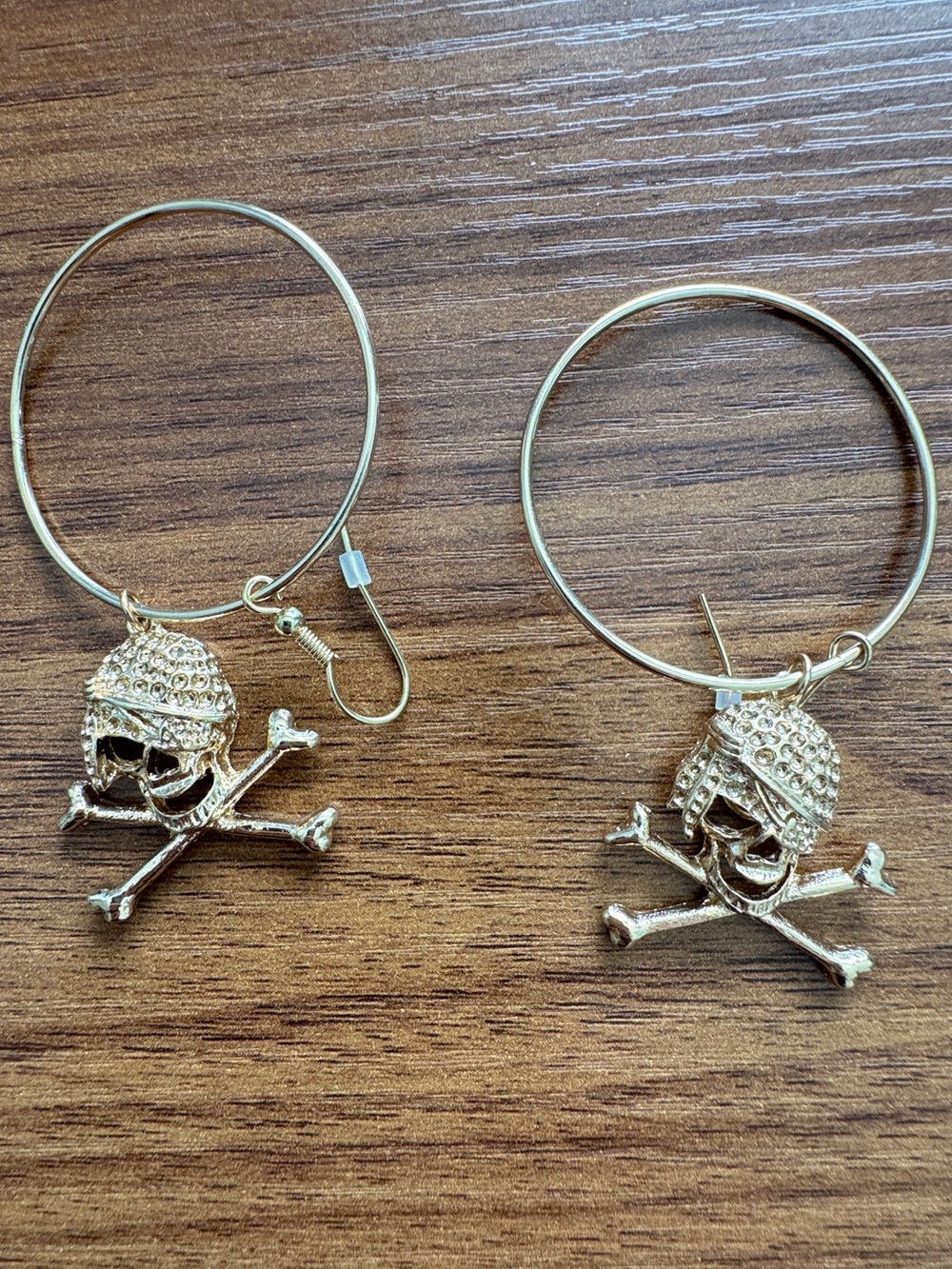 gold-plated hoop earrings with dangling skull and crossbones charms